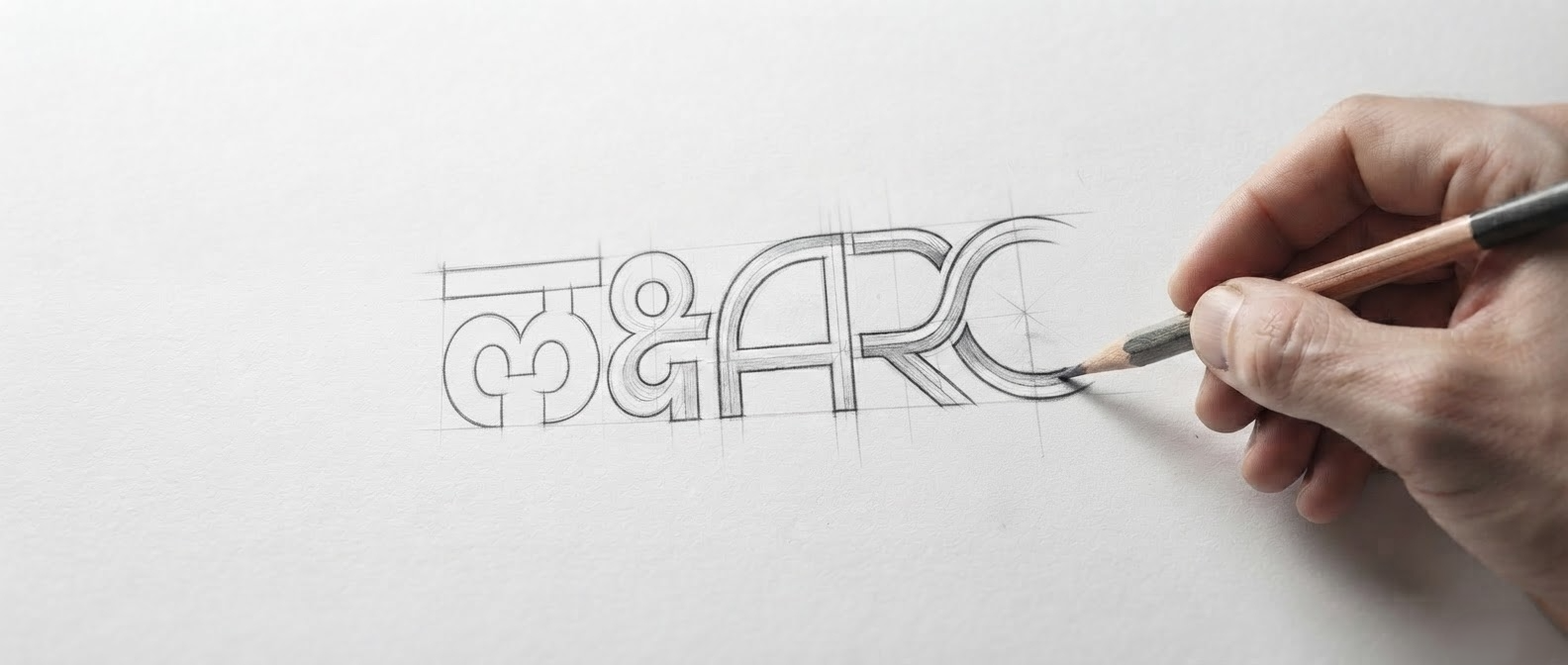 Laksharc Design logo being sketched by hand with a pencil on paper, demonstrating brand craftsmanship and design process